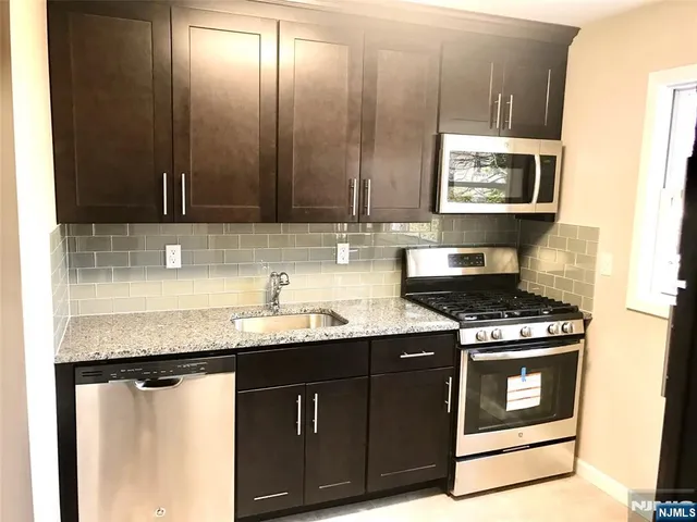 a kitchen with granite countertop a sink stove and cabinets