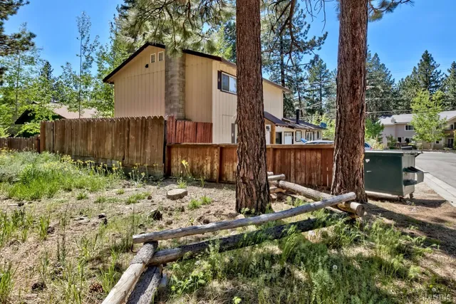 a view of a backyard with wooden fence and a bench