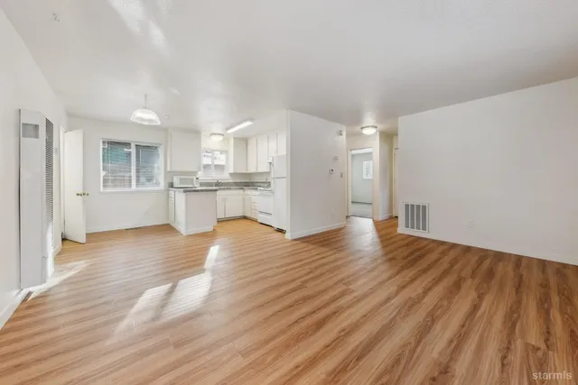 a kitchen with wooden floors white cabinets and stainless steel appliances