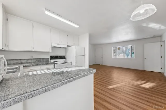 a kitchen with stainless steel appliances granite countertop a stove a sink and white cabinets