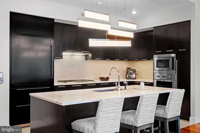 a kitchen with a sink a stove a refrigerator and chairs