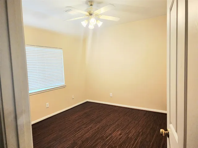 an empty room with wooden floor and fan
