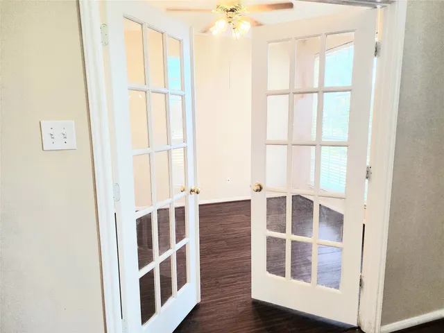a view of an empty room with wooden floor and windows