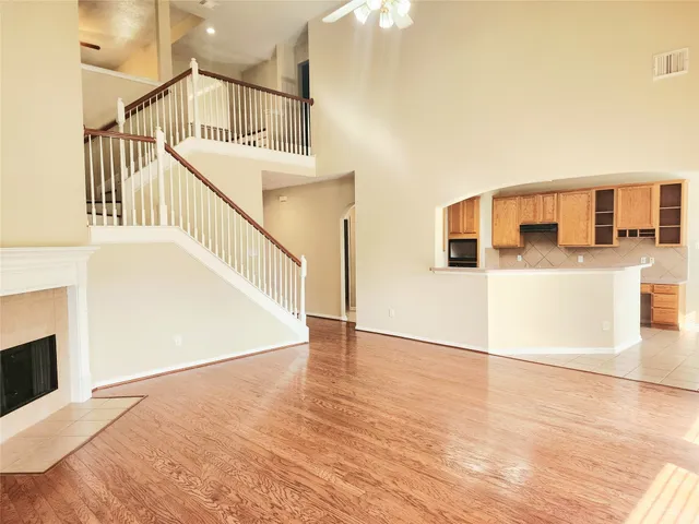 a view of a living room with wooden floor and a kitchen view