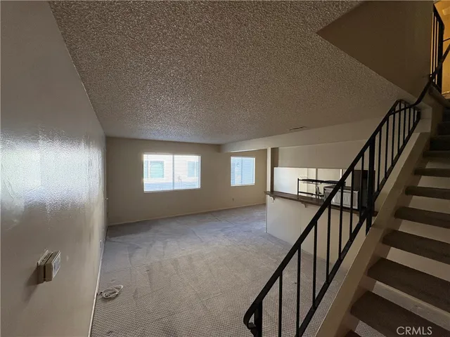 a view of an empty room with stairs and a window