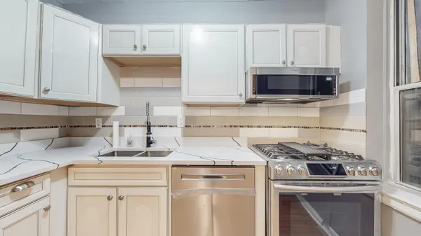 a kitchen with white cabinets and appliances