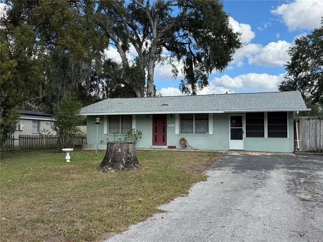a front view of a house with a garden and trees