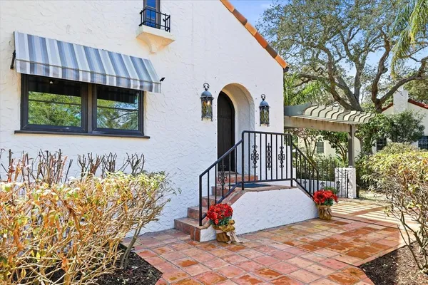 a view of a house with large trees and flower plants