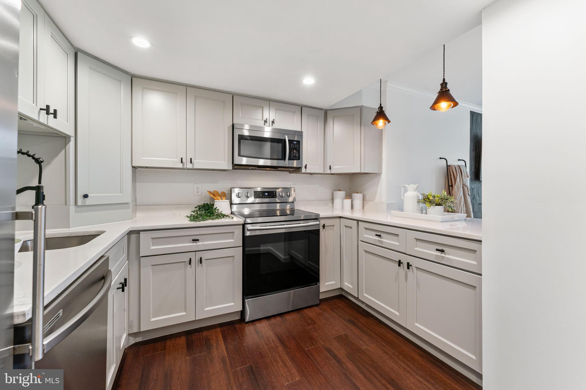 1700 17th Street Northwest, Unit 508 Washington, DC 20009 - Photo 3 of 24 a kitchen with stainless steel appliances white cabinets a sink a stove a microwave and wooden floors