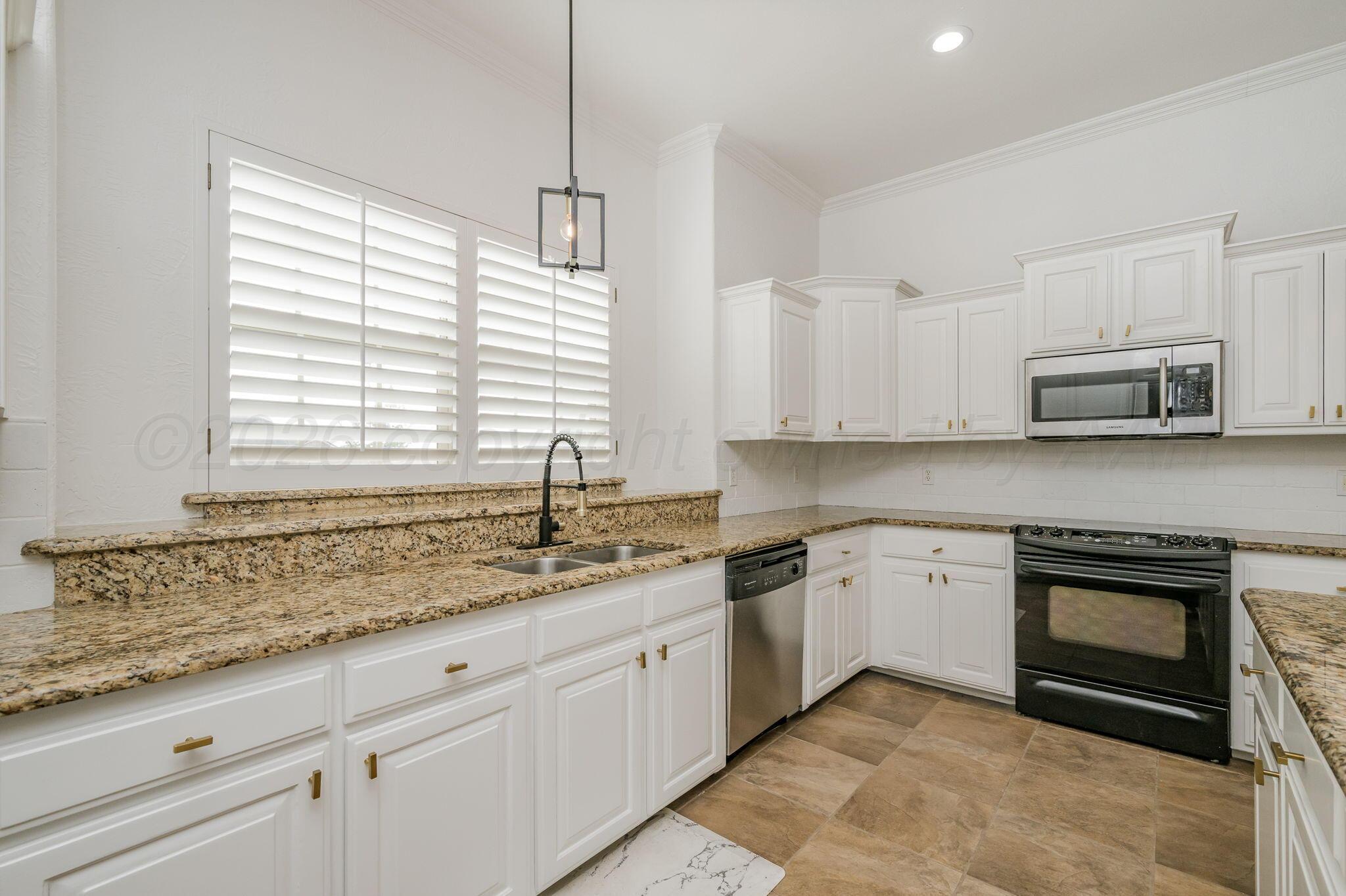 16700 Dove Meadow Road Canyon, TX 79015 - Photo 7 of 24 a kitchen with granite countertop white cabinets white appliances a sink and a window