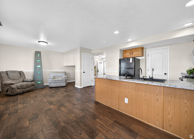 802 Sugar Maple Court Payson, UT 84651 - Photo 30 of 30 Kitchen featuring dark wood finished floors, freestanding refrigerator, open floor plan, a peninsula, and light stone countertops