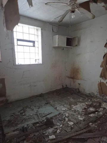 an empty room with a ceiling fan and window