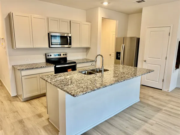 a kitchen with stainless steel appliances granite countertop a sink stove refrigerator and microwave