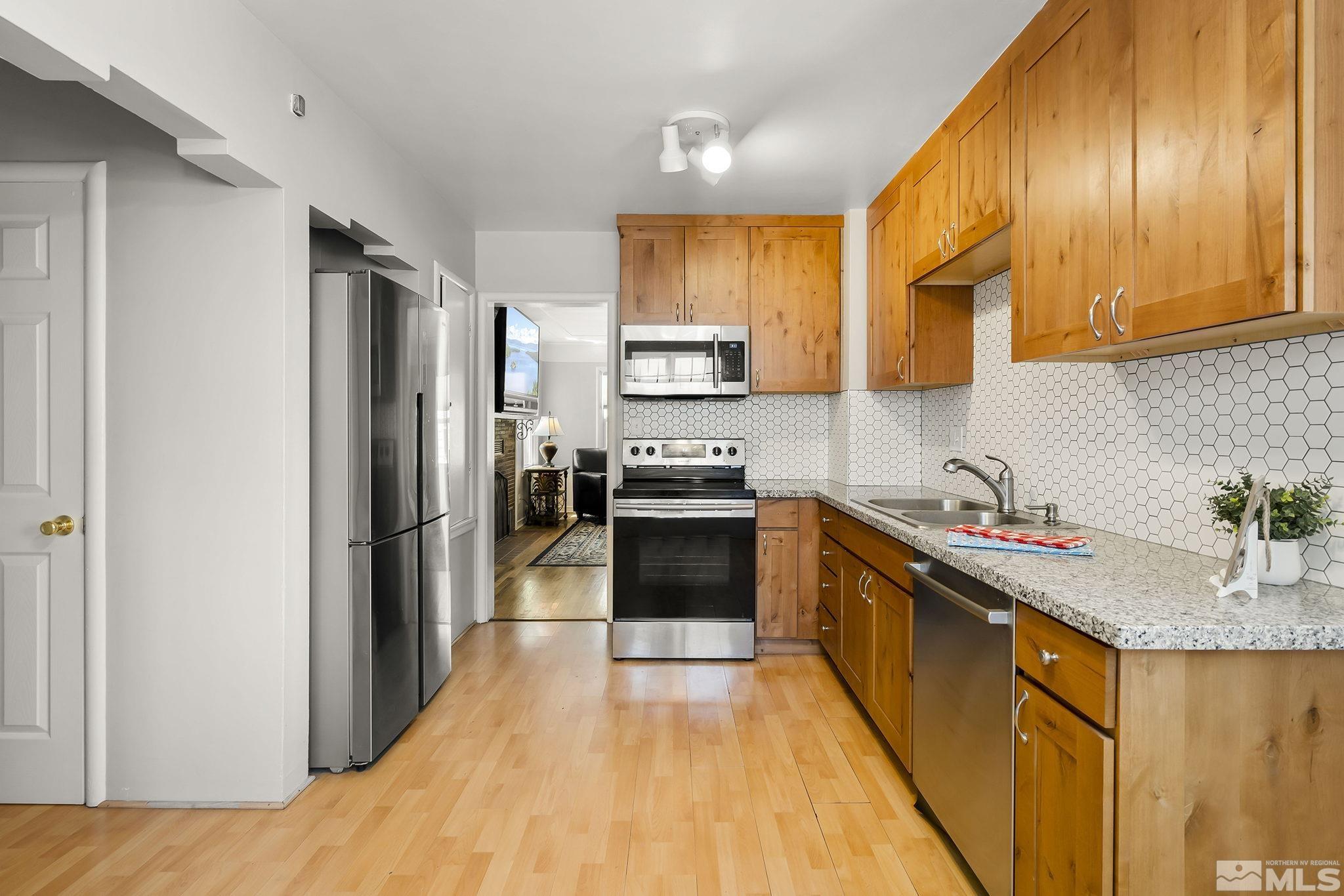 1124 Bon Rea Way Reno, NV 89503 - Photo 5 of 18 a kitchen with stainless steel appliances granite countertop a refrigerator a sink dishwasher a stove and a dining table with wooden floor