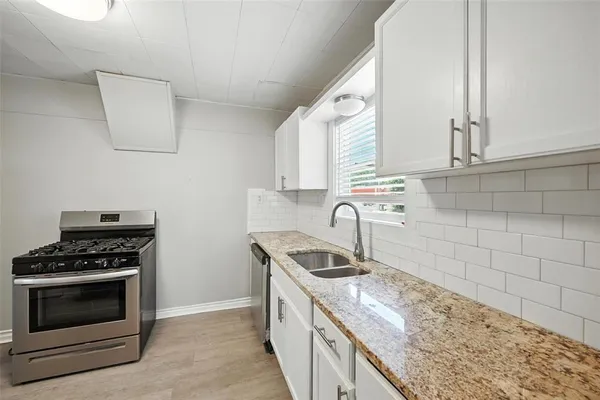 a kitchen with granite countertop a stove sink and cabinets
