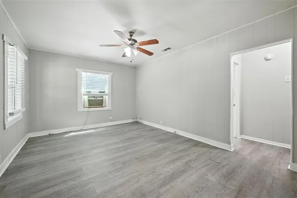 an empty room with wooden floor fan and windows