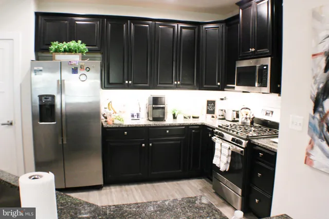 a kitchen with stainless steel appliances granite countertop a refrigerator and a stove
