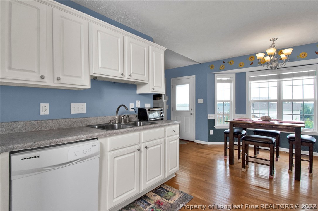 5415 Spreading Branch Road Hope Mills, NC 28348 - Photo 8 of 12 a kitchen with stainless steel appliances granite countertop a stove a sink dishwasher and white cabinets with wooden floor