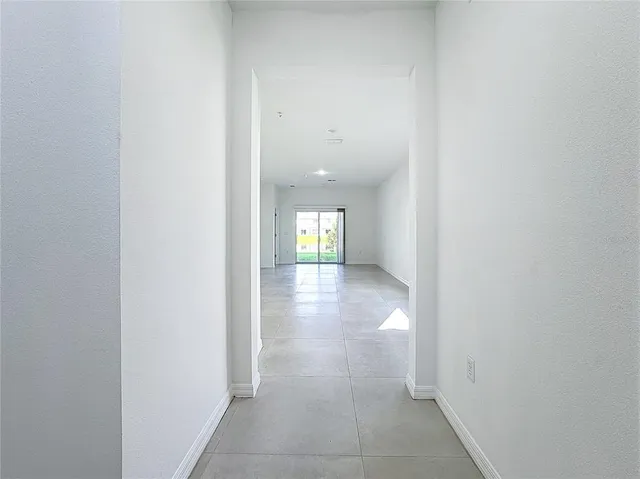 a view of a hallway with wooden floor and a bathroom