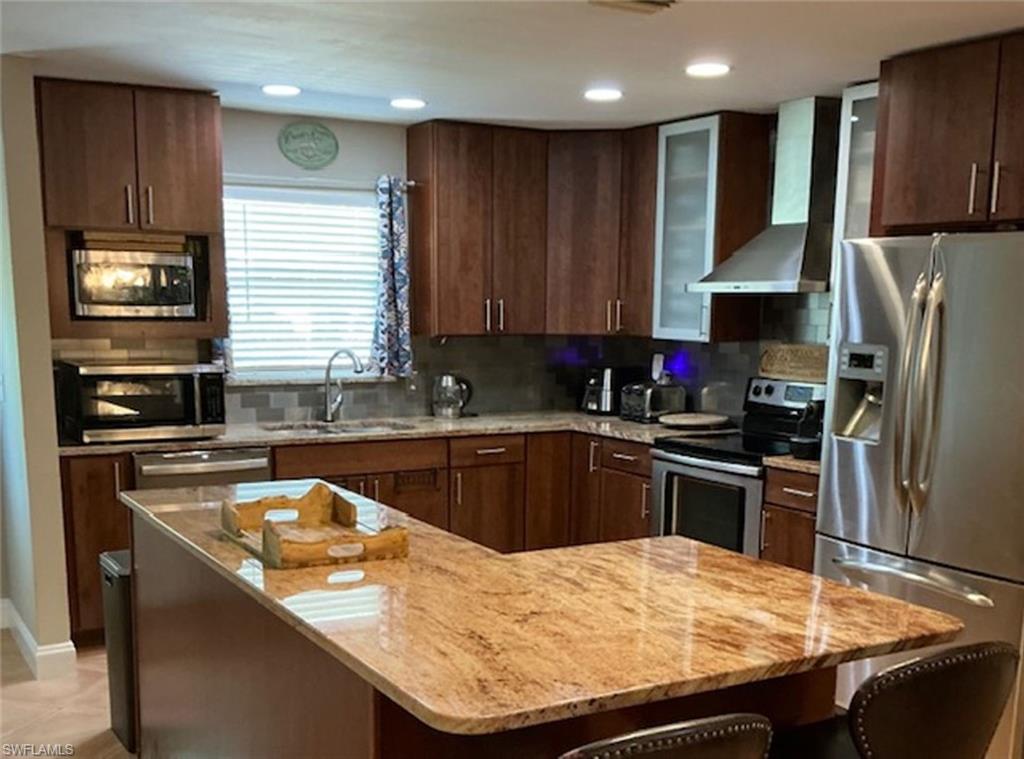 a kitchen with kitchen island granite countertop wooden cabinets a refrigerator and a sink