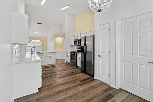 a kitchen with stainless steel appliances kitchen island wooden floors and white cabinets