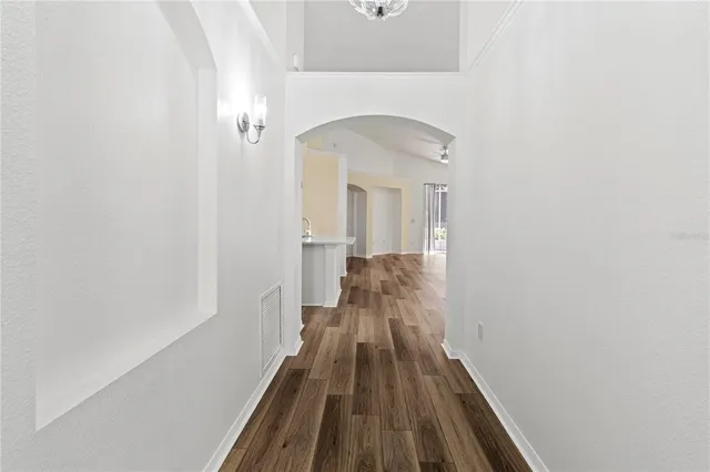 a view of a hallway with wooden floor and a bathroom
