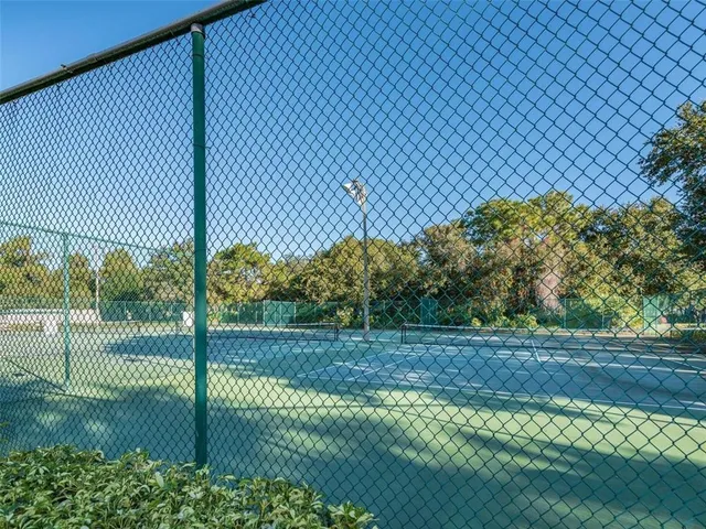 a view of a tennis ground with large trees