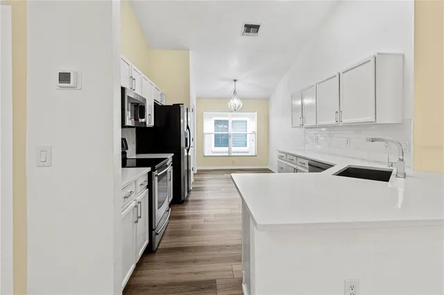 a kitchen with granite countertop a refrigerator a sink dishwasher a stove and a refrigerator with wooden floor