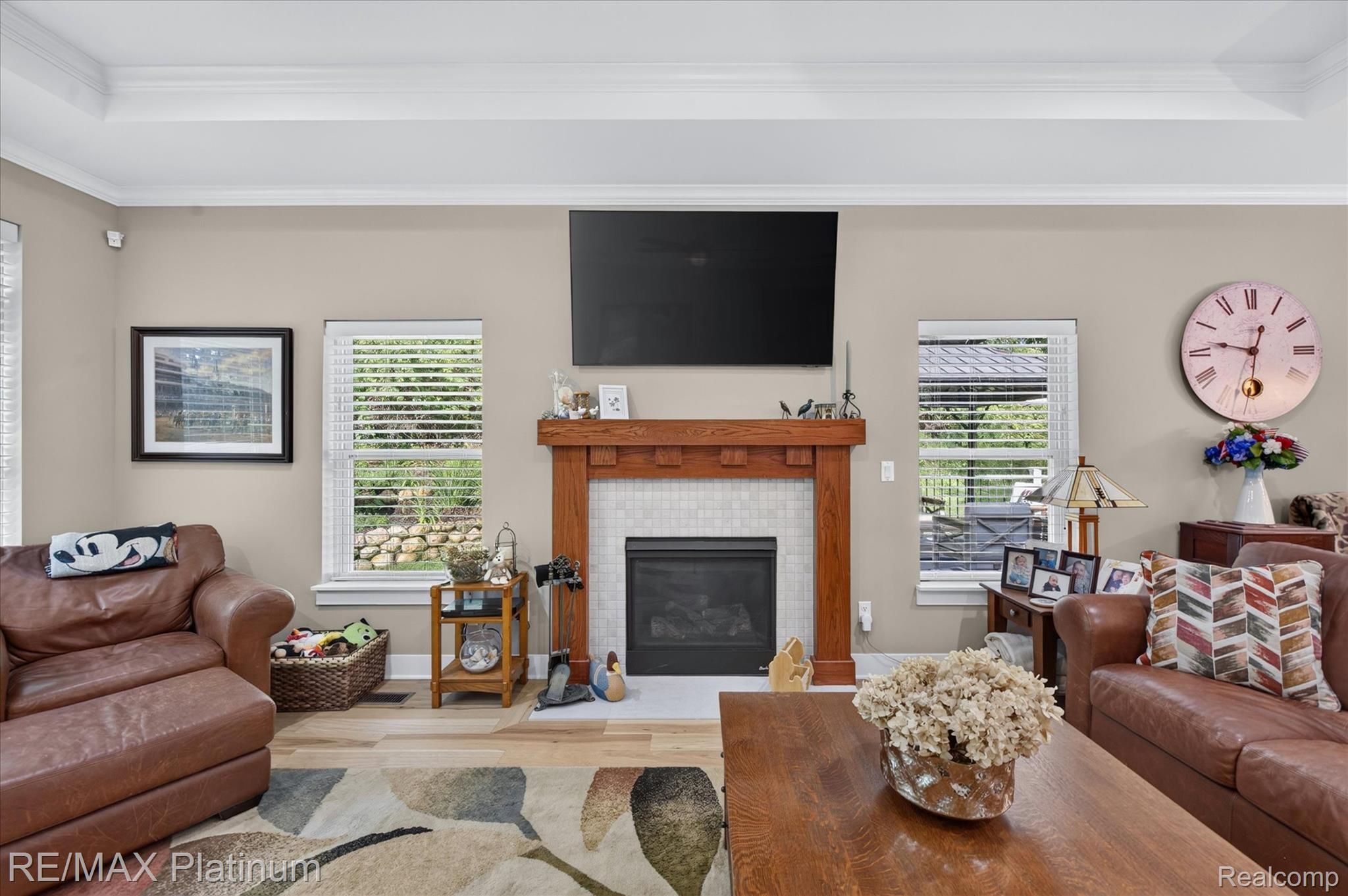2676 Crooked Lake Road Howell, MI 48843 - Photo 12 of 60 Living space featuring a prominent fireplace with a wood mantle and tile surround, recessed television, and light wood-finish flooring