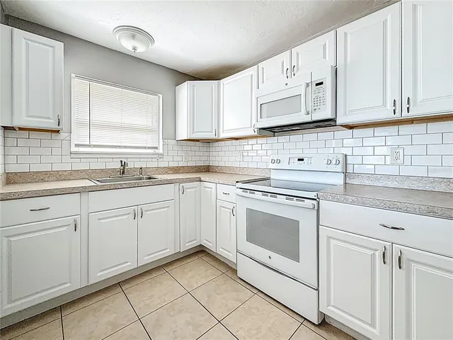 a kitchen with cabinets appliances a sink and a window