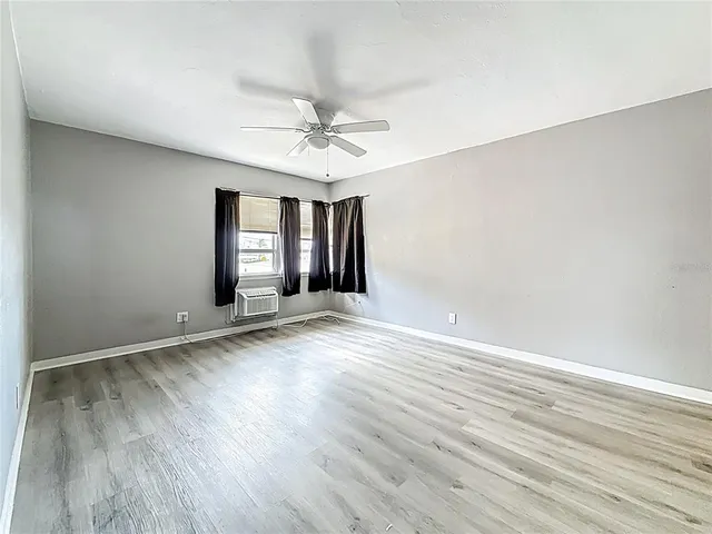 a view of an empty room with window and wooden floor