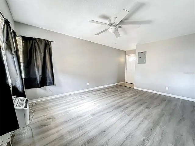 an empty room with wooden floor and fan