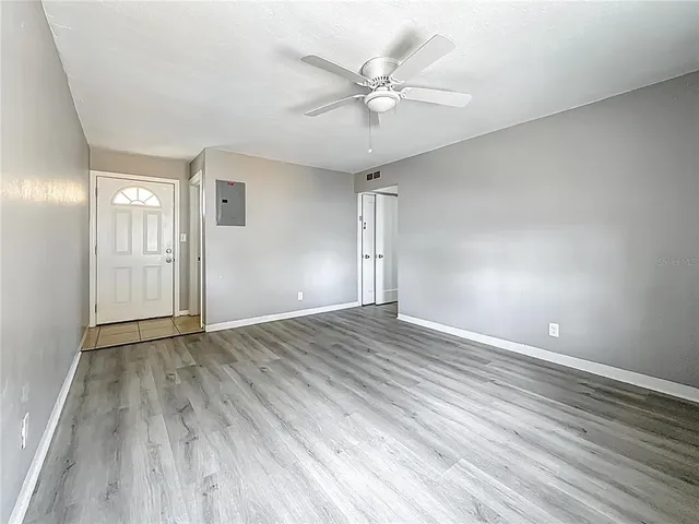 an empty room with wooden floor and fan