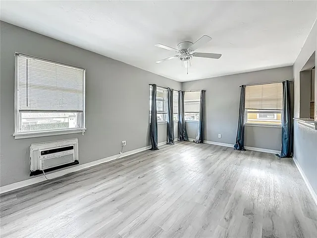 a view of an empty room with a window and wooden floor