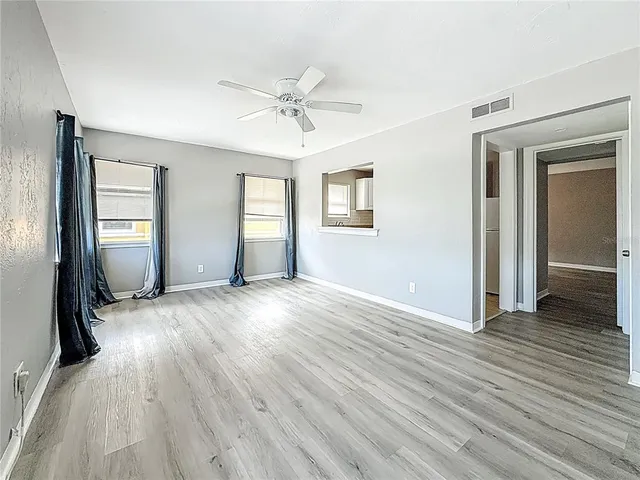 an empty room with wooden floor mirror and windows