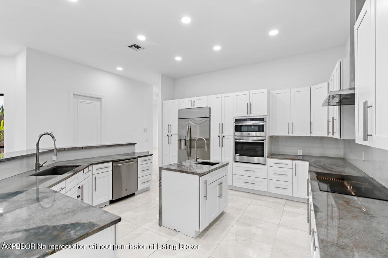 22771 El Dorado Drive Boca Raton, FL 33433 - Photo 4 of 24 a kitchen with kitchen island granite countertop a sink stove and cabinets