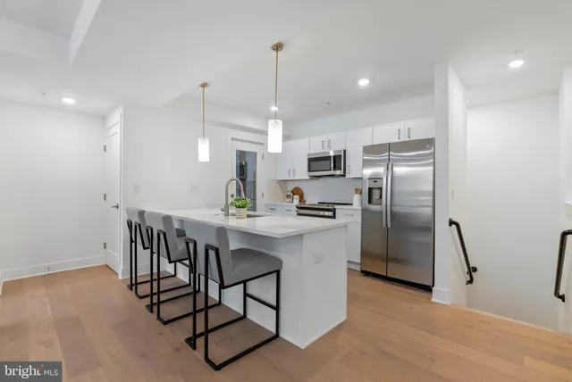 a kitchen with stainless steel appliances a dining table chairs refrigerator and microwave