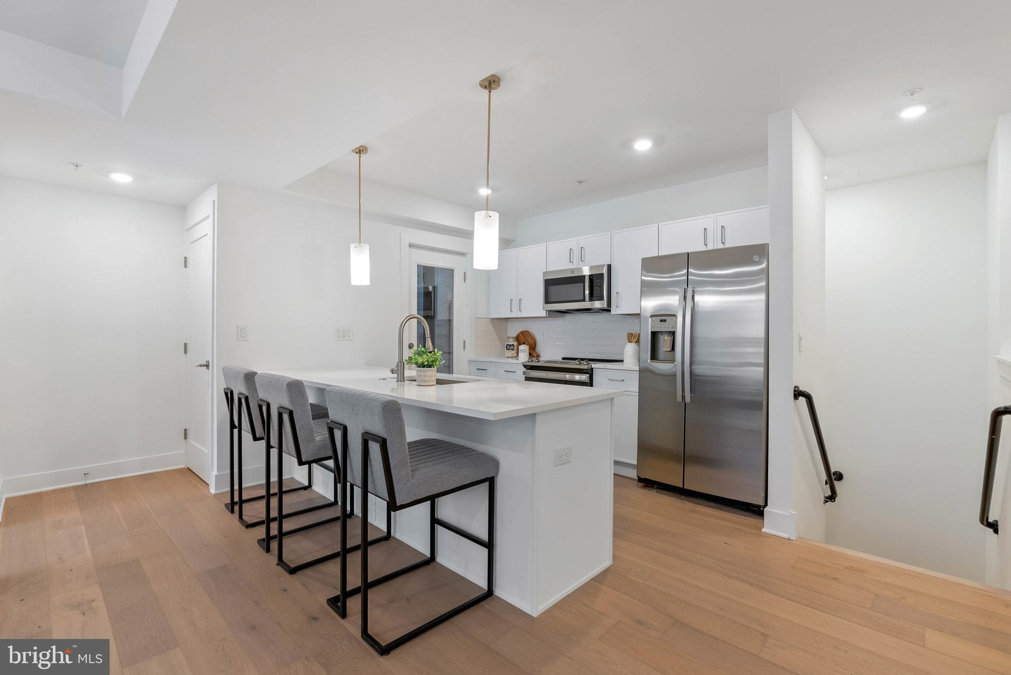 825 Bainbridge Street, Unit 101 Philadelphia, PA 19147 - Photo 2 of 27 a kitchen with stainless steel appliances a dining table chairs refrigerator and microwave