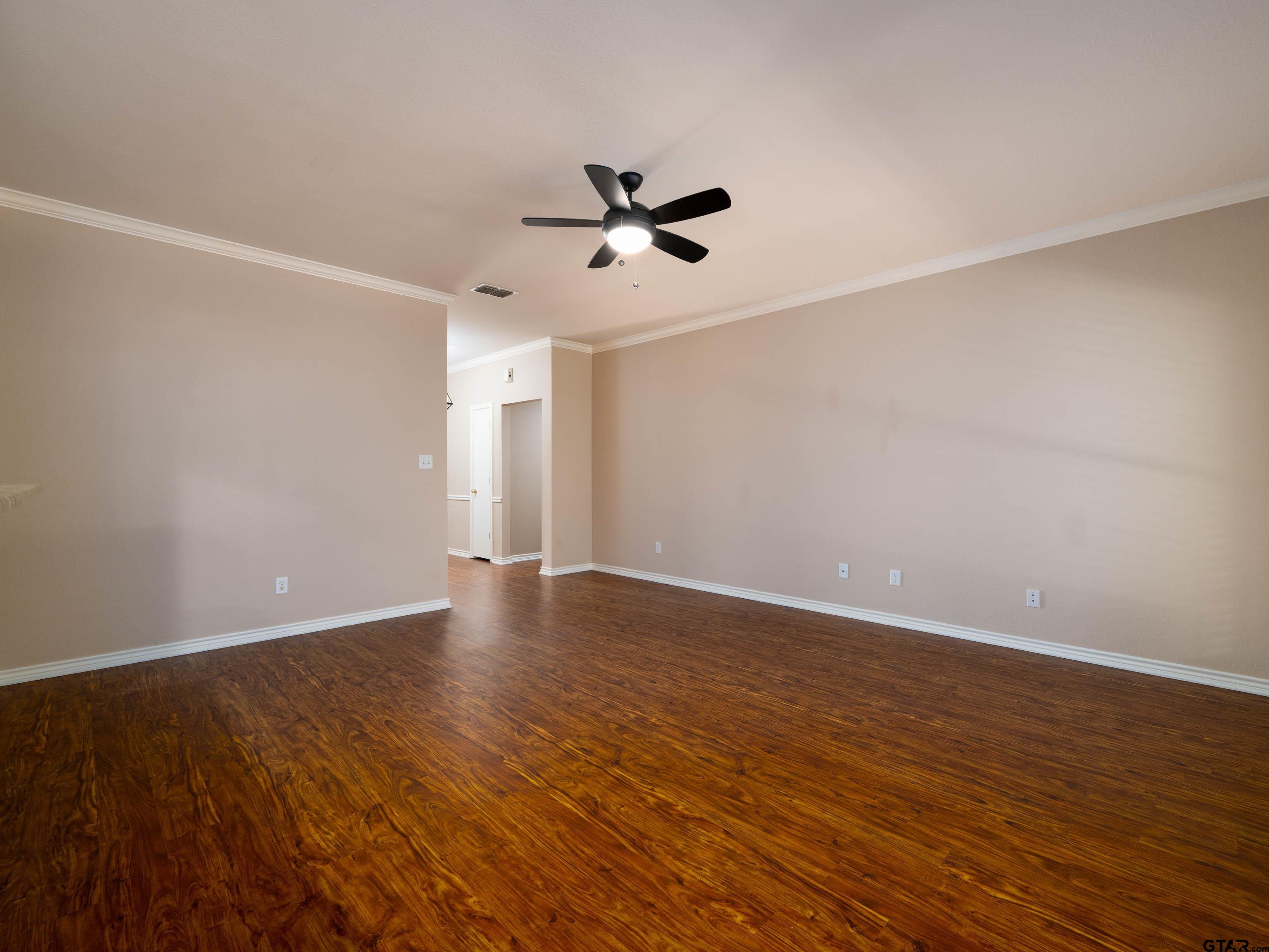 1521 Rice Road Tyler, TX 75703 - Photo 5 of 23 an empty room with wooden floor ceiling fan and windows