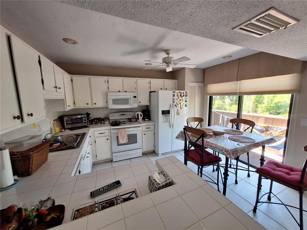 1697 Brookhouse Circle, Unit 217 Sarasota, FL 34231 - Photo 5 of 24 a kitchen with granite countertop lots of white cabinets stainless steel appliances dining table and chairs