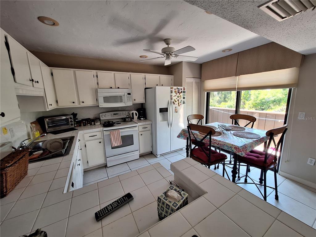 1697 Brookhouse Circle, Unit 217 Sarasota, FL 34231 - Photo 6 of 24 a kitchen with granite countertop a stove a sink dishwasher a dining table and chairs with wooden floor