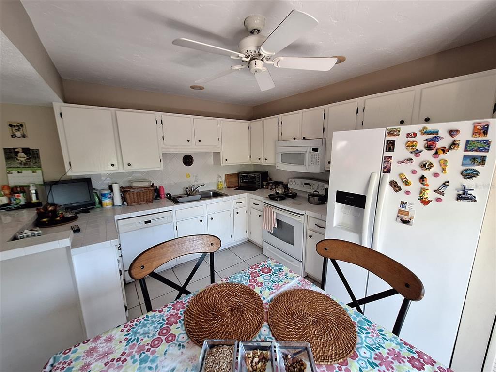 1697 Brookhouse Circle, Unit 217 Sarasota, FL 34231 - Photo 7 of 24 a kitchen with stainless steel appliances kitchen island granite countertop a dining table chairs and a refrigerator