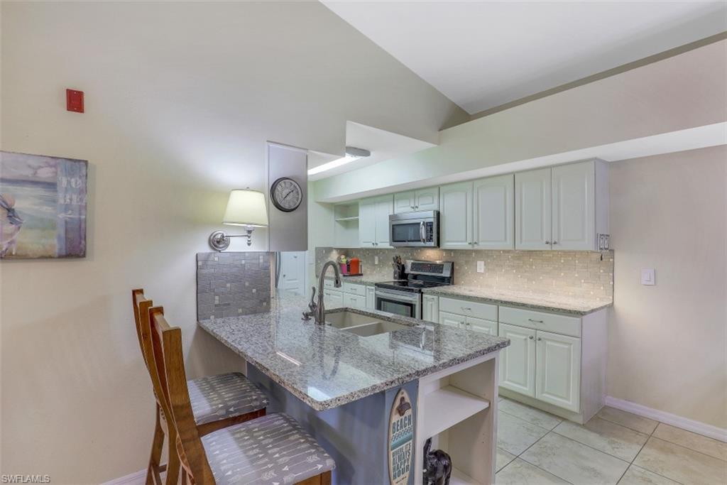 13621 Eagle Ridge Drive, Unit 1522 Fort Myers, FL 33912 - Photo 11 of 22 a kitchen with kitchen island a table and chairs in it