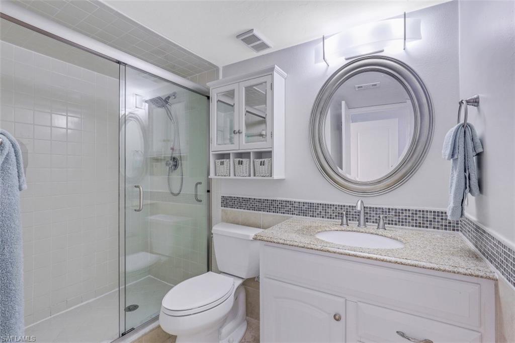 13621 Eagle Ridge Drive, Unit 1522 Fort Myers, FL 33912 - Photo 15 of 22 a bathroom with a granite countertop toilet a sink and a mirror