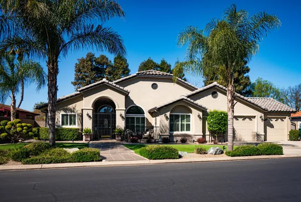 a front view of a house with a garden and trees