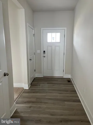a view of an empty room with wooden floor and closet