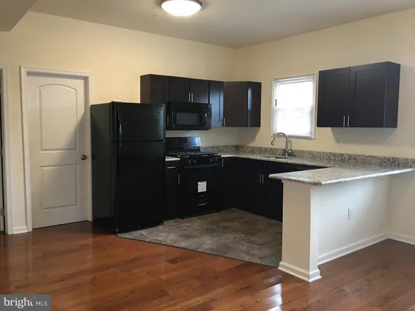 a kitchen with granite countertop a refrigerator and a sink