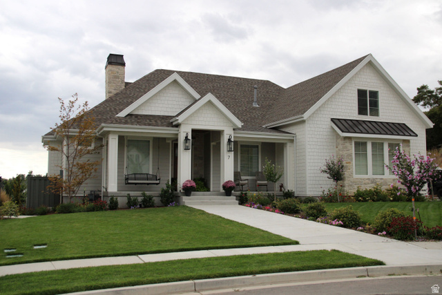 7 Elk Court Alpine, UT 84004 - Photo 1 of 10 Craftsman-style home featuring a prominent front porch, mixed material facade with white shingle siding and stone accents, a dark shingle roof, and a meticulously landscaped front yard with a concrete walkway