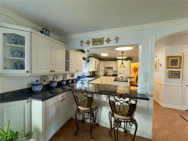 a kitchen with a dining table chairs cabinets and wooden floor