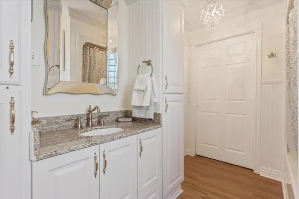 a kitchen with stainless steel appliances granite countertop a sink dishwasher a stove and white cabinets with wooden floor